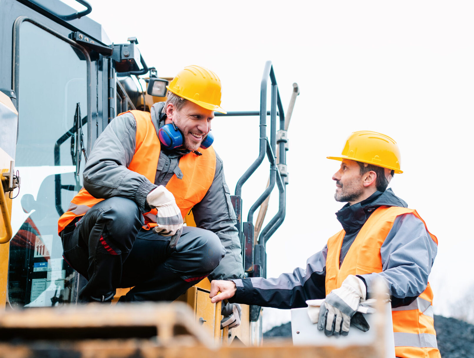 Foreman showing worker in open-cast mining pit direction with arm stretched